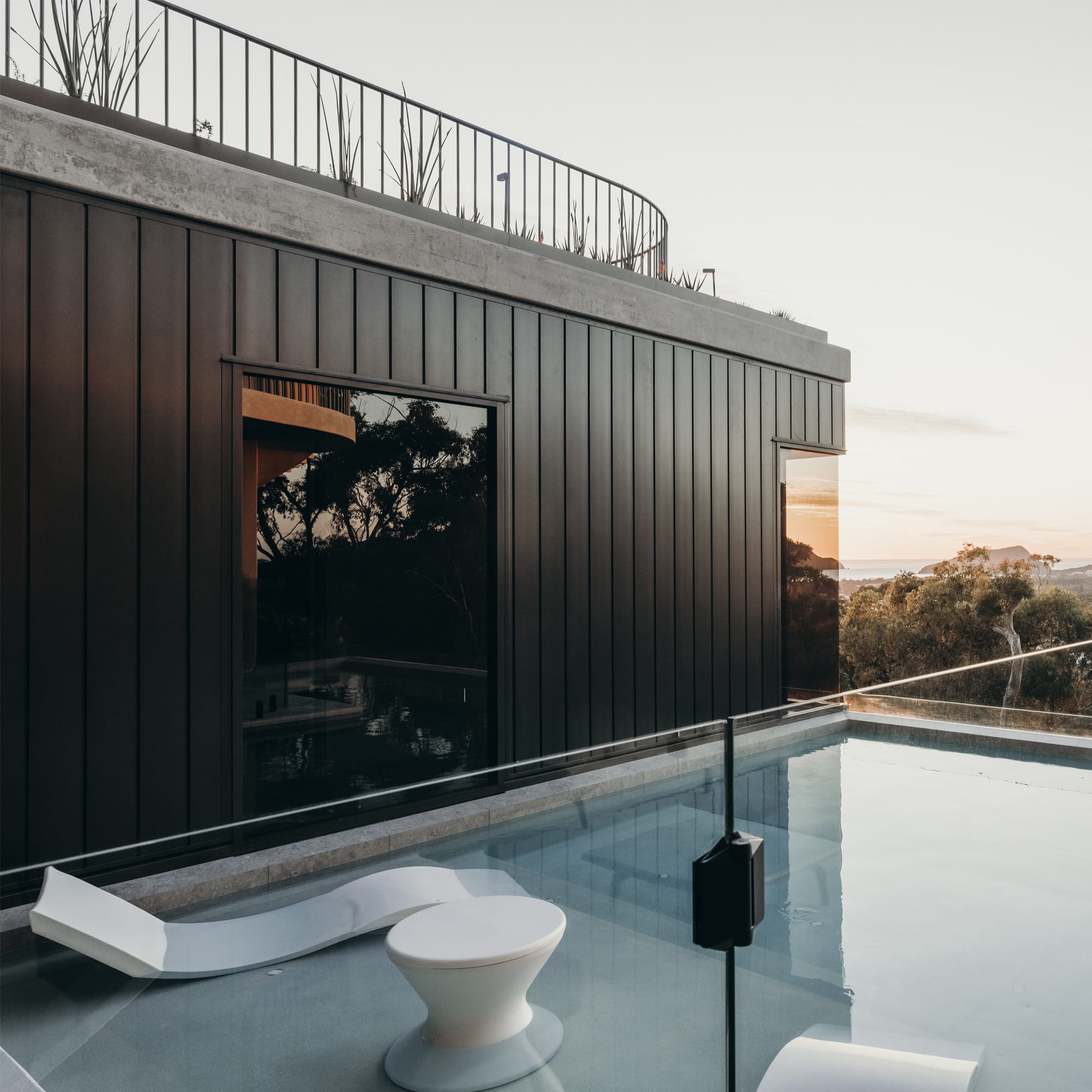 Dark aluminium cladding on a contemporary home beside a pool at dusk
