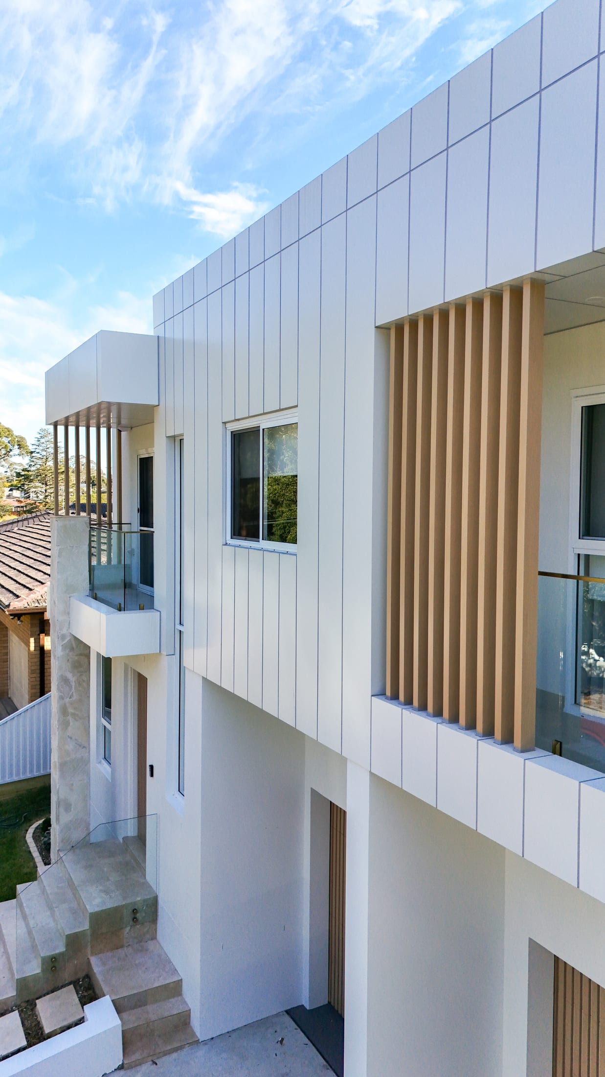 Contemporary white facade with vertical timber-look square batten feature panels