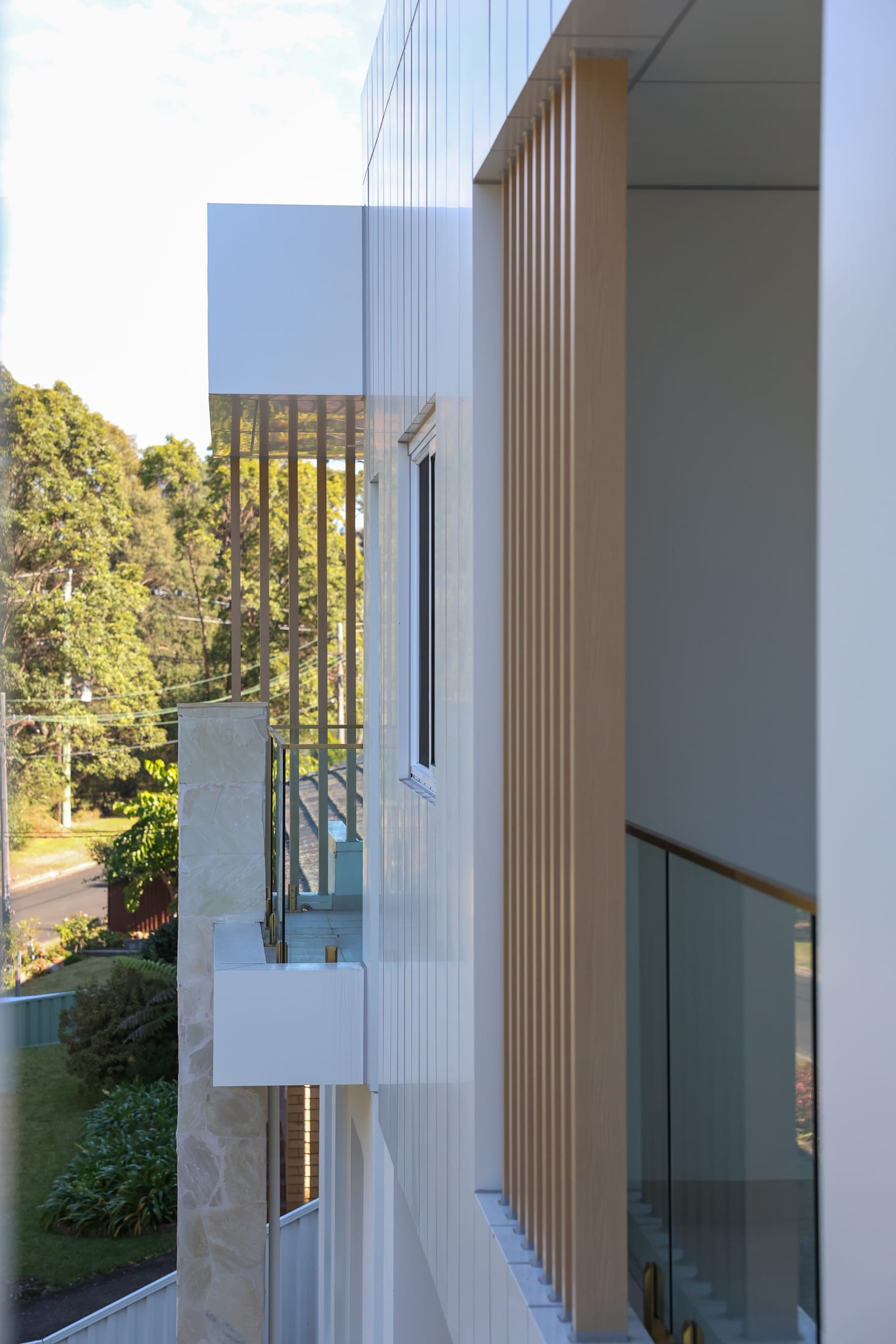 Vertical timber-look square batten screen on a white rendered facade